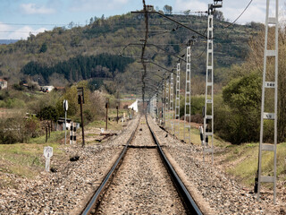 Train tracks are lost in the background under the electrified wires of the catenary in a landscape...