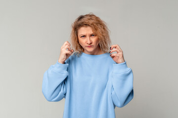 Aggressive angry middle age woman with curly blonde hair trying to fight at camera, shaking fists,...