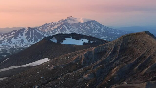 View of Mutnovsky volcano from the crater of Gorely volcano. Kamchatka peninsula, Russia. Aerial drone view. Beautiful landscape at sunrise.