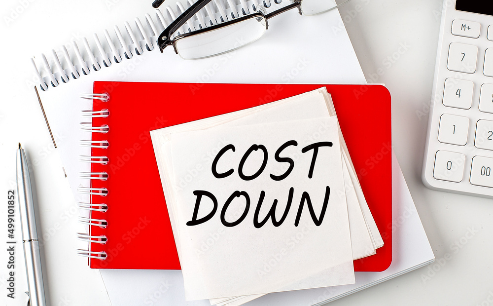 Poster cost down word on sticker on notepad with pen and calculator