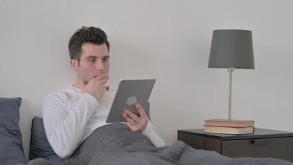 Man Reacting to Loss on Tablet while Sitting in Bed