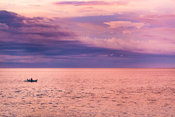 Fototapeta premium Pink sunset on the beach with small boat with fisherman
