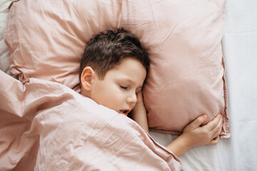 Fototapeta na wymiar The boy sleeps in the bedroom, head on a pillow, under a blanket