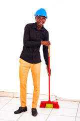 young man engineer holding a broom smiling.