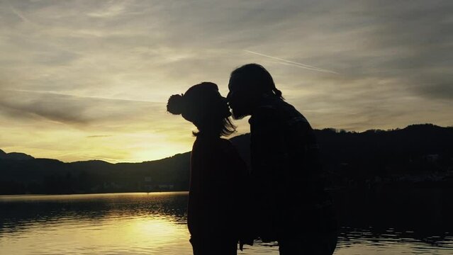 Silhouette of kissing couple against sunset at mountain top. Romantic scene of lovers kiss. Romance and activities for in love people in Saint Valentine's Day, Spain..