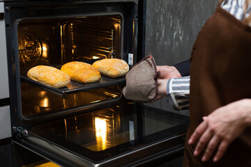 Close-up. The cook prepares bread in an electric oven.