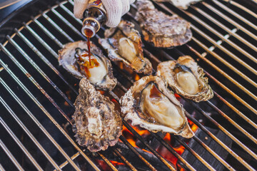 バーベキューで牡蠣に醤油をかける