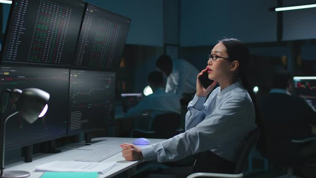 Stock market trader buying and selling over the phone looking at computer screens