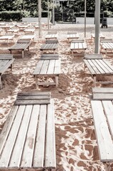 Sun loungers on the beach near the sea. Empty resort. Chaise lounge - beach wooden furniture for the summer. Wooden sunbed on the sandy sea coast.