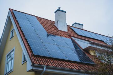 Close-up of solar panels installed on historic building gable roof with chimney. Private home using...