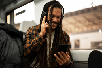 Young man listening the music while traveling by a train. Handsome young man traveling by a train