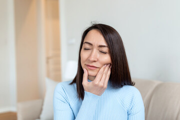 Portrait of unhappy Asian woman suffering from toothache at home. Healthcare, dental health and problem concept. Stock photo