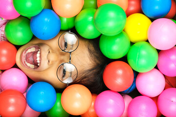 Little girl playing colorful Plastic ball on playground. cute little girl lying on a colorful ball
