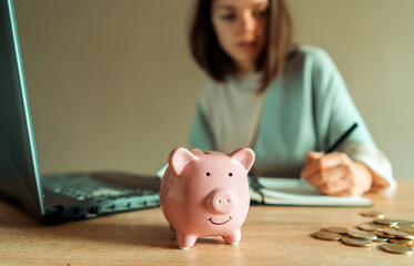 Obraz na płótnie Canvas Girl makes calculations, puts funds in a piggy bank.