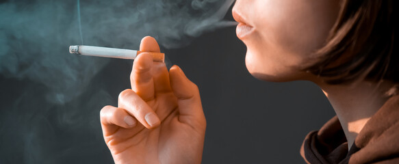 Woman is smoking, holding a cigarette in her hand.