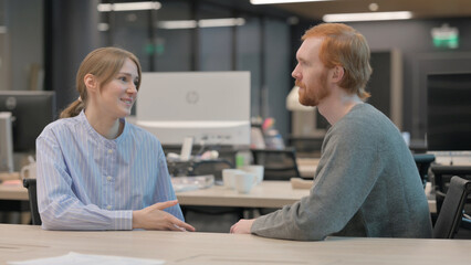 Young Woman Talking to Young Man in Office