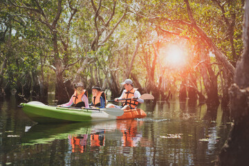asian family sailing sea kayak in mangrove forest