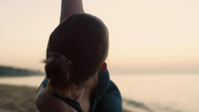 Yoga girl practicing triangl pose on beach close up. Woman training flexibility.