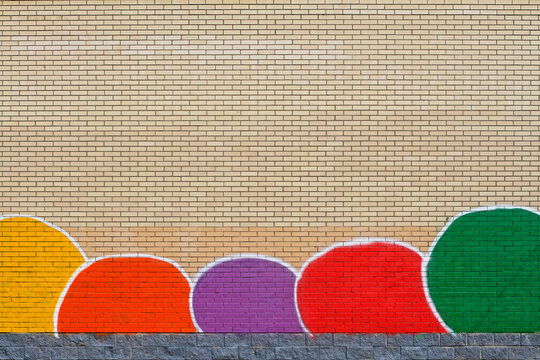 Yellow brick wall with a painted lower part in the form of multi-colored spots and grey tiles