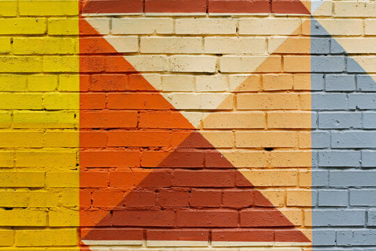 Colorful (yellow, orange, beige, brown and grey) painted brick wall as background, texture
