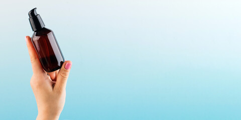A mock-up of a brown dispenser with a natural cosmetic product in a woman's hand on a blue background. Zero West.