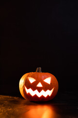Moody scary Halloween pumpkin jack o'lantern with glowing eyes on dark background
