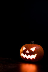 Moody scary Halloween pumpkin jack o'lantern with glowing eyes on dark background