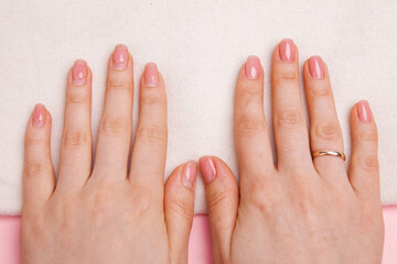 girl's nails with regrown gel coating, untidy and well-groomed hand with fresh manicure gentle nude coating.