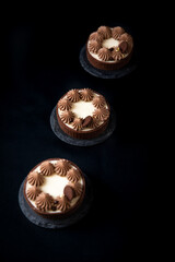 Tarte Schoko-Cheesecake. Feiner Cheesecake mit natürlicher Vanilleschote und einer haube aus Schokolade. Schrarze Hintergrund. 