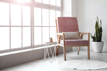 Stylish pink armchair in interior of room