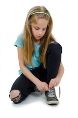 Beautiful little girl tying shoelaces, copy space. Isolated on white background