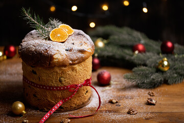 Rustic homemade Christmas traditional Italian holiday panettone cake with festive ribbon, decoration and lights