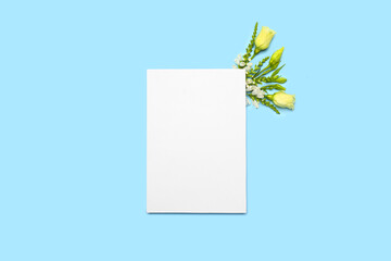 Blank sheet of paper and flowers on blue background