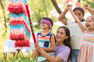 Woman and cute children at pinata birthday party