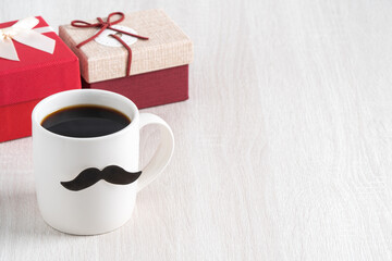 Father's day design concept. Close up of cup of coffee and gift box for daddy.