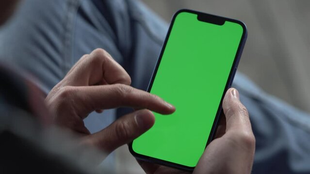 Man Using Smartphone in Vertical Mode with Green Mock-up Screen. Internet Social Networks Browsing News, Financial Reports
