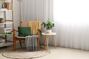 Comfortable armchair and houseplant on table in room