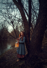 Girl standing near big tree in night spring park with  lantern