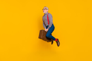Full body photo of funny grey haired pensioner flying around world on old retro bag isolated on yellow color background