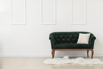 New green sofa with pillow near white wall