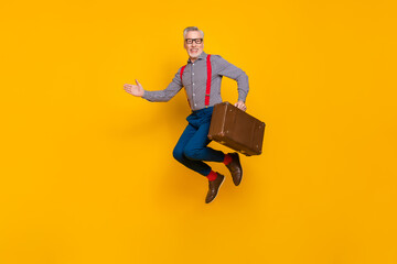 Full size positive attractive male hold retro luggage meet friend shake person hand isolated on yellow color background