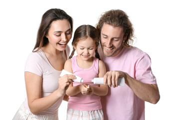 Parents applying tooth paste onto their daughter's brush on white background
