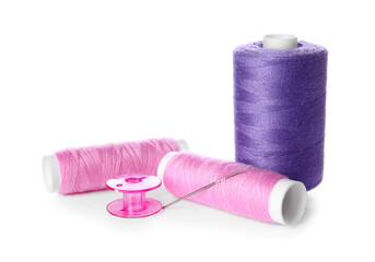 Thread spools with needle on white background