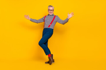 Full length photo of cheerful good mood grandpa dancing in nightclub wear suspenders isolated on yellow color background