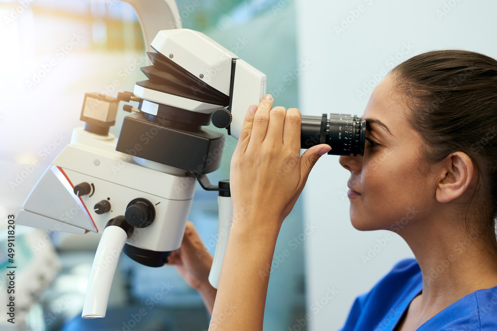 Poster taking a closer look. shot of a young pathologist looking at samples under a microscope.