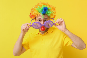 Funny young man in disguise on yellow background. April fools' day celebration