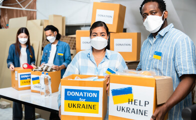 Group of volunteers African ,asian  man and asian woman preparing food donations for people in need in Ukrain., Humanitarian aid concept.