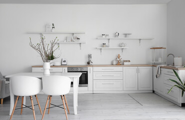 Interior of stylish kitchen with dining table, counters and shelves with kitchenware