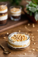 Snickers toffee cream peanut layered dessert in a glass jar on a wooden background