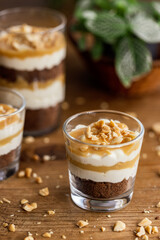 Snickers toffee cream peanut layered dessert in a glass jar on a wooden background
